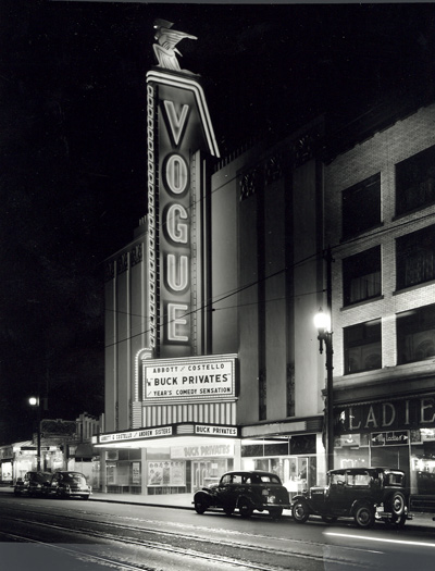 General view of Vogue Theatre, showing the tall sign tower that dominates the facade, outlined in neon and surmounted by a stylized figure of the goddess Diana. © Vancouver Public Library, Historical Photo Collection, 33461.