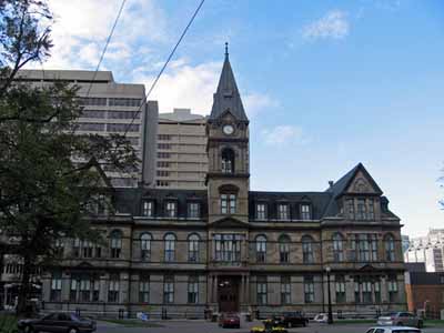 Exterior view of Halifax City Hall, showing the three-storey massing, and the seven-storey clock tower with its clock and its steeply angled roof, 2006. © Parks Canada Agency / Agence Parcs Canada, 2006.