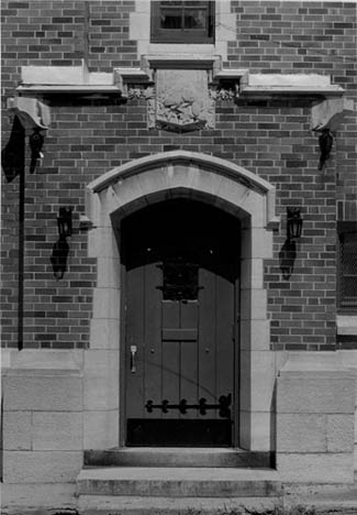 General view of the Salaberry Armoury, showing a concentric Tudor entrance arch and carved plaque, 1989. © Parks Canada Agency / Agence Parcs Canada, Henri Langlois, 1989.