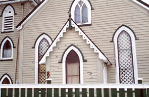 Vue du porche de l'église Christ Church de Quidi Vidi, qui montre la façade à trois baies avec une porte centrale flanquée de fenêtres en arc tiers-point sous des larmiers, 1994. © Parks Canada Agency / Agence Parcs Canada, J. Butterill, 1994.