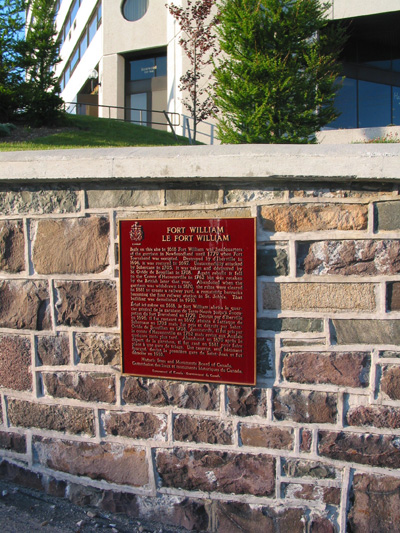 Vue générale de la plaque de la Commission des lieux et monuments historiques du Canada deu fort William situé dans le centre-ville de St. John’s, devant l’hôtel Fairmont Newfoundland, sur un mur de soutènement à l’angle de la place Cavendish et de la rue (© Parks Canada Agency / Agence Parcs Canada, M. Dawe, 2005.)