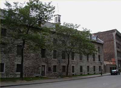 Façade of the Grey Nuns' Hospital, showing the three-and-a-half storey volume under a prominent, gable ended roof, and rough masonry construction, 2004. © Parks Canada Agency / Agence Parcs Canada, 2004.