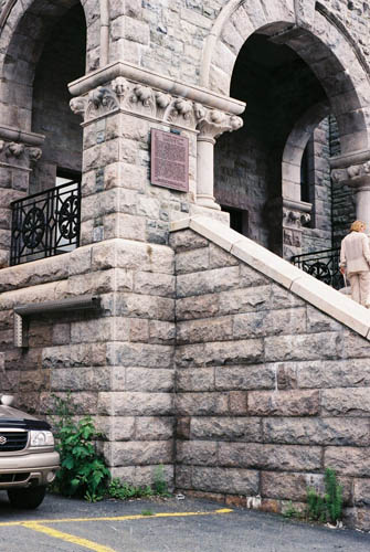 Detail view of of St. John's Court House's entrance showing the plaque as well as its stone staircase, and arched portico with decorative stonework including voussoirs, keystone, columns, balustraded balcony and carved motifs, 2005. © Parks Canada | Parcs Canada
