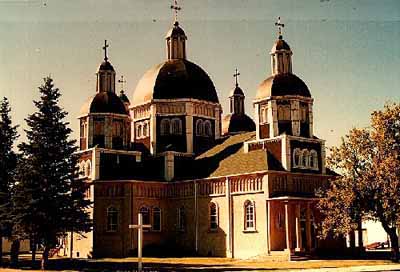 General view of the Ukrainian Catholic Church of the Resurrection, showing the tight massing of its towers, many roof levels and four secondary domes around a large central dome, 1996. © Parks Canada Agency / Agence Parcs Canada, 1996.