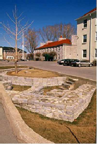 General view of Fort Frontenac, showing sections of the north curtain wall and the west curtain wall in a traffic circle at the intersection of Ontario Street and Place D’Armes, 1995. (© Parks Canada Agency / Agence Parcs Canada, J. Butterill, 1995.)