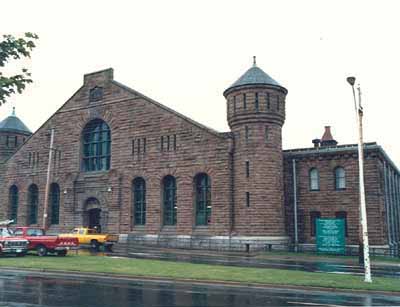 Corner view of a façade of Halifax Drill Hall, showing the entrance, 1990. © Department of National Defence/ Ministère de la Défence nationale, 1990.