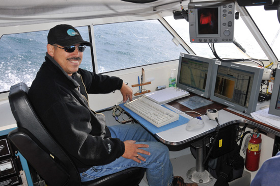 Hydrographer Roger Cameron at work station aboard launch Kinglett en route to O’Reilly Island
