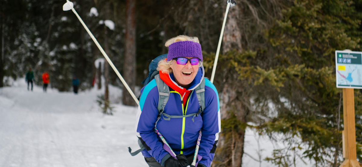 Un skieur de fond s'élance dans une descente avec le sourire.
