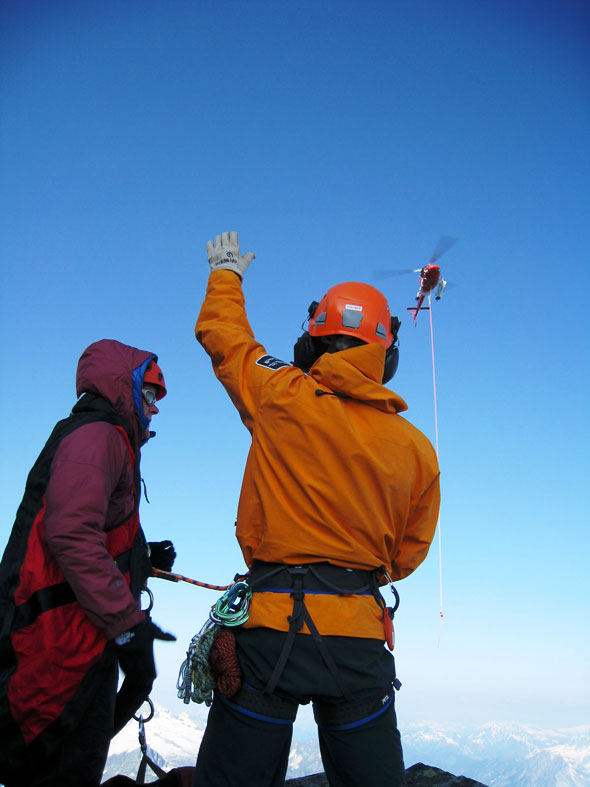 Un spécialiste de la Sécurité des visiteurs se prépare à saisir la corde pour se faire héliporter en compagnie du premier alpiniste. 