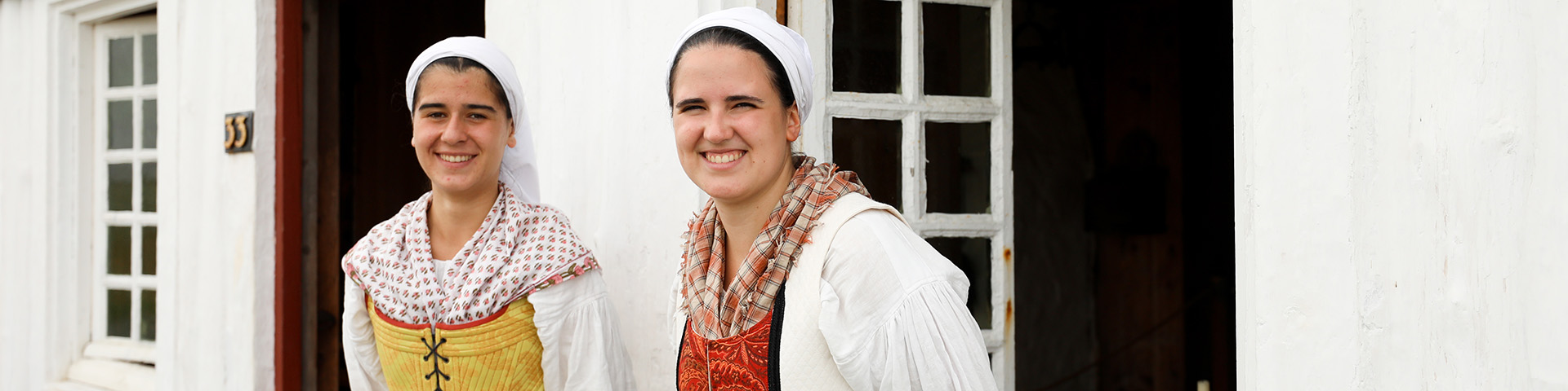 Two women smile at the camera wearing traditional Basque costumes