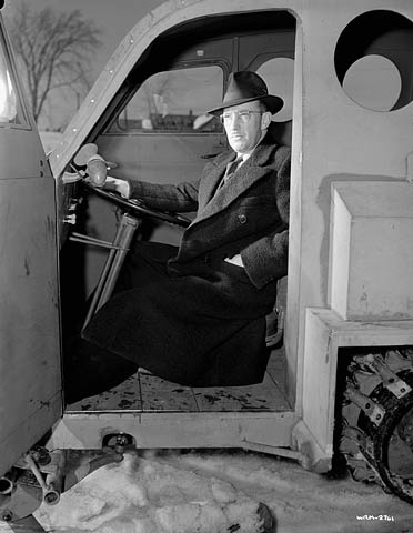 Joseph Armand Bombardier poses, seated at the wheel of the Bombardier military snowmobile. (© National Film Board of Canada. Photothèque / Library and Archives Canada // Office National du Film du Canada. Photothèque / Bibliothèque et Archives Canada)