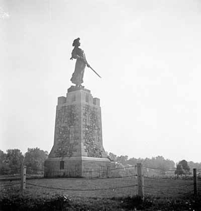 Historical view of Madeleine de Verchères, showing the bronze statue set atop a tapered conical tower, 1934. © Library and Archives Canada | Bibliothèque et Archives Canada, PA-056837, C. M. Johnson, 1934.