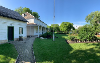 View of general store and Seven Oaks House with gardens from entrance gate on south side. (Jeffrey Thorsteinson, Parks Canada, July 2022) © Parks Canada | Parcs Canada, Jeffrey Thorsteinson, 2022.