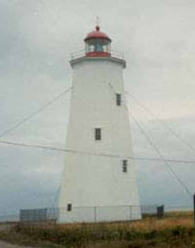 General view of Miscou Island National Historic Site of Canada, showing its colour scheme characteristic of lighthouses and its polygonal lantern set behind a cast iron rail, 1990. © Agence Parcs Canada / Parks Canada Agency, Ministry of Transport, 1990.