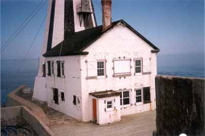 Vue du phare de Gannet Rock, où l'on peut apercevoir ses murs en béton armé, ses volets en bois et l’accès direct au phare depuis chaque étage de la résidence, 1999. © Canadian Coast Guard / Garde côtière canadienne, 1999.