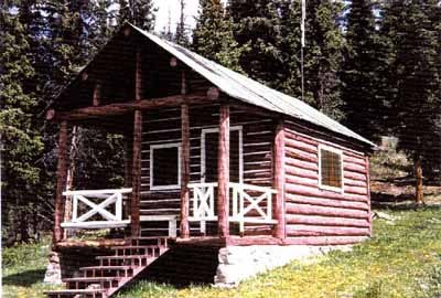 Corner view of Medicine Tent Warden Cabin, showing its log-framed sheltered porch area at the entrance gable, 1996. © Parks Canada Agency / Agence Parcs Canada, 1996.