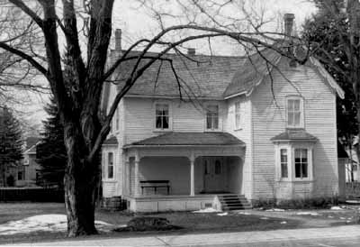 Vue de la façade est de la maison Bethune, qui montre le plan asymétrique en L sur deux étages, 1989. © Agence Parcs Canada / Parks Canada Agency, 1989.