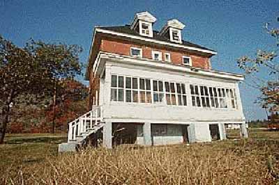 View of Building 77, showing the southern elevation with a large verandah that has been converted into a solarium, circa 2004. © Agence Parcs Canada / Parks Canada Agency, circa / vers 2004.