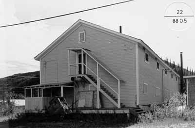 Corner view of the Mess Hall and Bunkhouse, showing the arrangement and detailing of its doors and windows, its porches, and its covered stair, 1988. (© Parks Canada Agency / Agence Parcs Canada, 1988.)