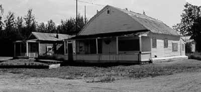 Corner view of the V.I.P. Guest House, showing the distinctive gambrel-like shape of the roof and the front verandah, 1988. (© Parks Canada Agency / Agence Parcs Canada, 1988.)