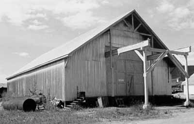 Corner view of Warehouse No. 3, showing the front double doors and the overhanging roof, 1988. (© Parks Canada Agency / Agence Parcs Canada, 1988.)