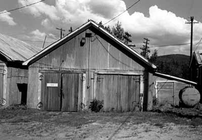 Façade of the Garage and Storage Building, showing the building’s simple, rectangular form, gable roofs and large double doors, 1988. (© Parks Canada Agency / Agence Parcs Canada, 1988.)