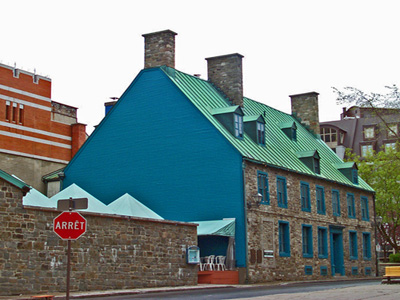 Vue générale de la Maison Maillou qui montre sa toit très incliné à deux versants avec petites lucarnes à pignon et les cheminées en pierre, 2003. © Parks Canada Agency / Agence Parcs Canada, 2003.
