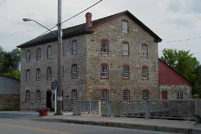 Corner view of the Old Stone Mill, showing its composition of five-bay façades with three-bay end elevations, 2004. © Parks Canada Agency / Agence Parcs Canada, 2004.