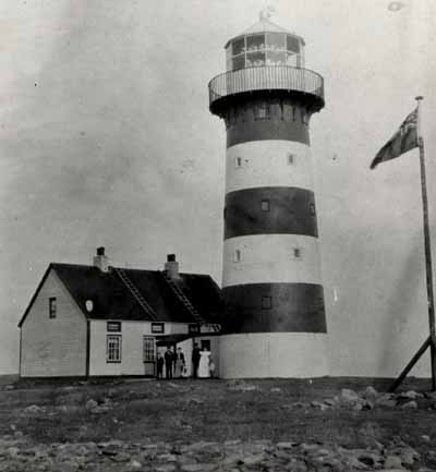 View of Cape Pine Lighthouse, showing the form and massing of the 15.3 metre high structure which consists of a tall, tapered tower with twelve-sided lantern. © Agence Parcs Canada / Parks Canada Agency.
