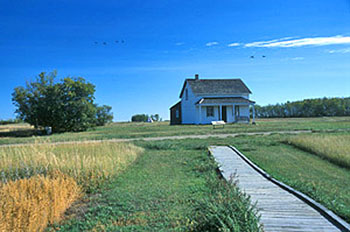 Panoramic view of the Former Jean Caron Sr. House emphasizing its overall design and materials that harmonize with the historic setting, 2003. © Parks Canada Agency / Agence Parcs Canada, D. Venne, 2003.