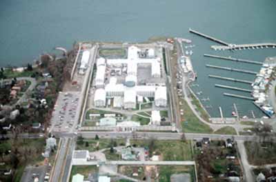 Aerial view of Kingston Penitentiary, showing the Greek cross (Auburn style) footprint of the original cellblock with its four three-storey wings, 1991. © Parks Canada Agency / Agence Parcs Canada, J.P. Jérôme, 1991.