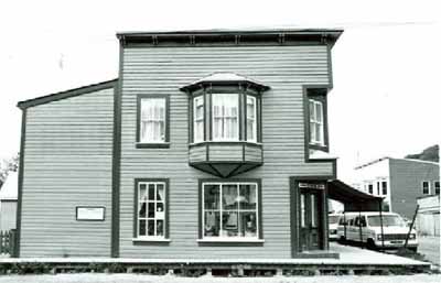 Side view of Mme. Tremblay's Store, showing the inset and splayed corner window, and the oriel window, 1987. © Department of the Environment / Ministère de l'Environnement, 1987.