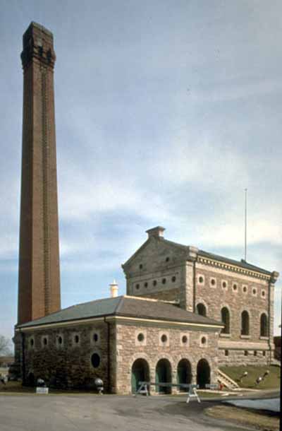 View of the Hamilton Waterworks complex, showing the tall chimney and the distinctive Italianate profile of the original waterworks pumphouse, 1993. © Parks Canada Agency/Agence Parcs Canada, 1993.