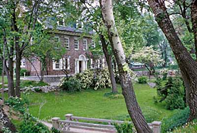 Panoramic view of the Hough House emphasizing its domestic scale, Colonial Revival style, and stone and wood materials which harmonize with its park-like landscape at the National Historic Site, 1960. © Parks Canada Agency / Agence Parcs Canada, 1960.