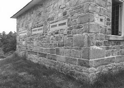 Vue en angle de la résidence fortifiée du maître-éclusier de Jones Falls, qui montre les murs extérieurs en blocs de pierre rustiquée, 1989. © Parks Canada Agency / Agence Parcs Canada, 1989.