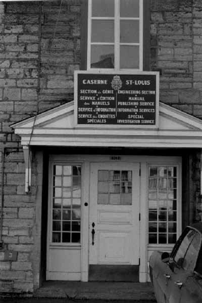 Vue de l'entrée principale de la caserne Saint-Louis, qui montre l’ouvrage de maçonnerie, dont moellons bruts posés en assise et brique, 1969. © Agence Parcs Canada / Parks Canada Agency, 1969.