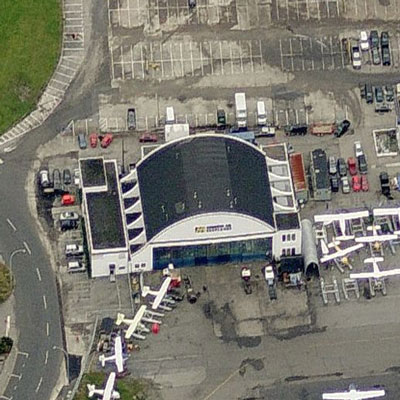 Arial view of the Harbour Air Hangar, Building T-018, showing the simplicity and asymmetry of the principal façade with its two-storey tower at the southwest corner featuring a flat roof and balanced punctuation of narrow vertical windows, 2011. © Microsoft Bing Maps, 2011.