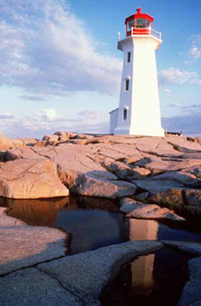 General view of the Lighthouse at Peggy’s Point, demonstrating its relationship with the site, which consists of a barren rock outcrop and natural vegetation without visible paths leading to the building or any other structures in the immediate vicinity,  © Department of Fisheries & Oceans Canada | Département de pêches et océans Canada, 1995