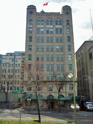 Front facade of the National Press Building showing the small towers at the roofline and the extensive glazing, and the arched windows of the ground floor and top floor, 2011. © Parks Canada Agency / Agence Parcs Canada, M. Therrien, 2011.