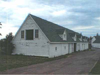 View of the exterior of Building 16, showing the steeply pitched gable roof with long eave line, low eaves and gable-roofed dormers, 2000. © Department of Agriculture and Agri-Food / Ministère de l'Agriculture et de l'Agroalimentaire, Ed Charmley, 2000.