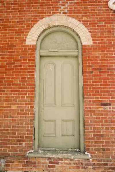 View of the exterior of Former Atha School House, showing the round-headed upper panelling of the door, 2005. © Department of Public Works and Government Services / Ministère des Travaux publics et services gouvernementaux, Alice Da Silva, 2005.