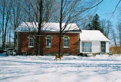 General view of Former Atha School House, showing the clean, simple lines and massing composed of a one-storey, rectangular brick block capped with a broad gable roof, 2005. © Department of Public Works and Government Services / Ministère des Travaux publics et services gouvernementaux, Alice Da Silva, 2005.
