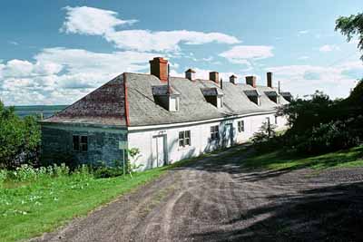 General view of Building 16 showing the wood frame hipped roof with dormers and masonry chimneys, circa 2004. (© Parks Canada Agency | Agence Parcs Canada, circa | vers 2004)