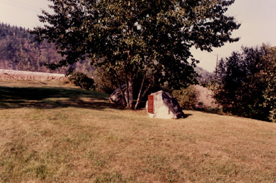 Vue de l'endroit de la plaque de la Commission des lieux et monuments historiques du Canada sur une roche sur le terrain de la résidence du commissaire © Parks Canada Agency | Agence Parcs Canada, 1990.