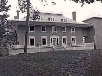 General view of the Manoir Papineau, showing the building’s strong massing composed of an imposing central core that rises to a broken hip roof with wide eaves, 2001. © Parks Canada | Parcs Canada, Yvan Fortier, 2001.