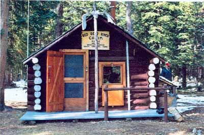 View of the main entrance to the Sandhills Warden Cabin, showing the entrance door to one side counterbalanced by a window, 1996. © Agence Parcs Canada / Parks Canada Agency, 1996.