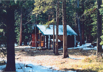Corner view of the Sandhills Warden Cabin, showing the rectangular plan, and gabled roof clad in cedar-shingles, 1996. © Agence Parcs Canada / Parks Canada Agency, 1996.