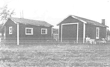 À gauche, vue générale des façades est et nord du Hangar à bois, 1992. (© Department of Public Works / Ministère des Travaux publics, (A & E Services -- CPS, WRO), 1992.)