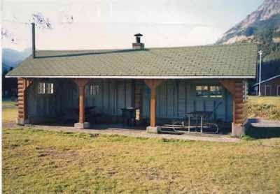 Vue de l’abri-cuisine 13, qui montre le volume bas et simple de ce bâtiment d’un étage,  fermé sur trois côtés, 1990. (© Agence Parcs Canada / Parks Canada Agency, 1990.)