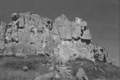 Vue des dramatiques falaises verticales de grès et les formations rocheuses des cheminées de fées à Áísínai'pi, 2002. © Parks Canada Agency/ Agence Parks Canada, 2002.